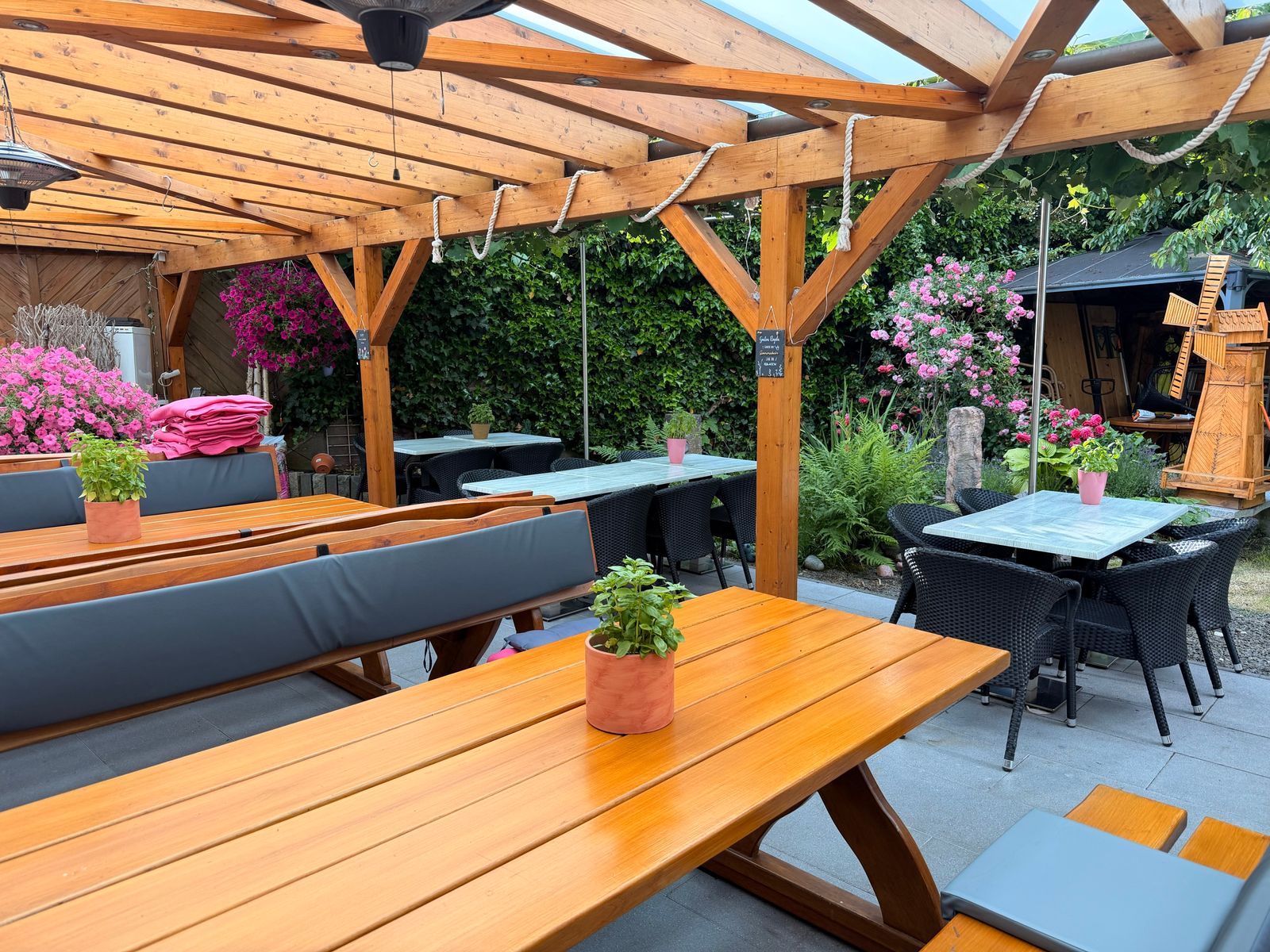 Überdachter Biergarten im Gasthaus Großenohl in Gummersbach-Derschlag — Holztische unter der Pergola, Blumen und viel Grün